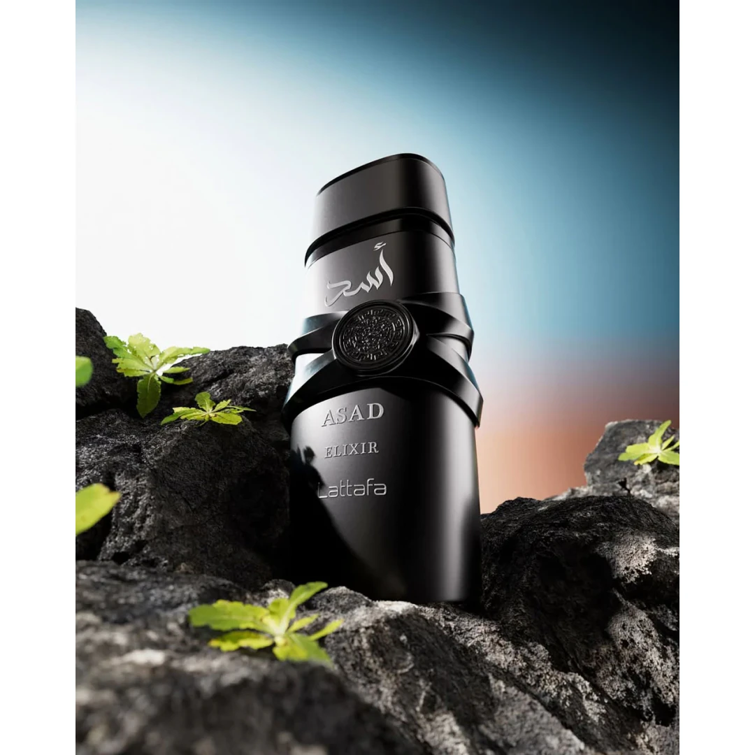 Frasco preto de perfume ASAD ELIXIR Lattafa sobre pedras escuras e plantas verdes