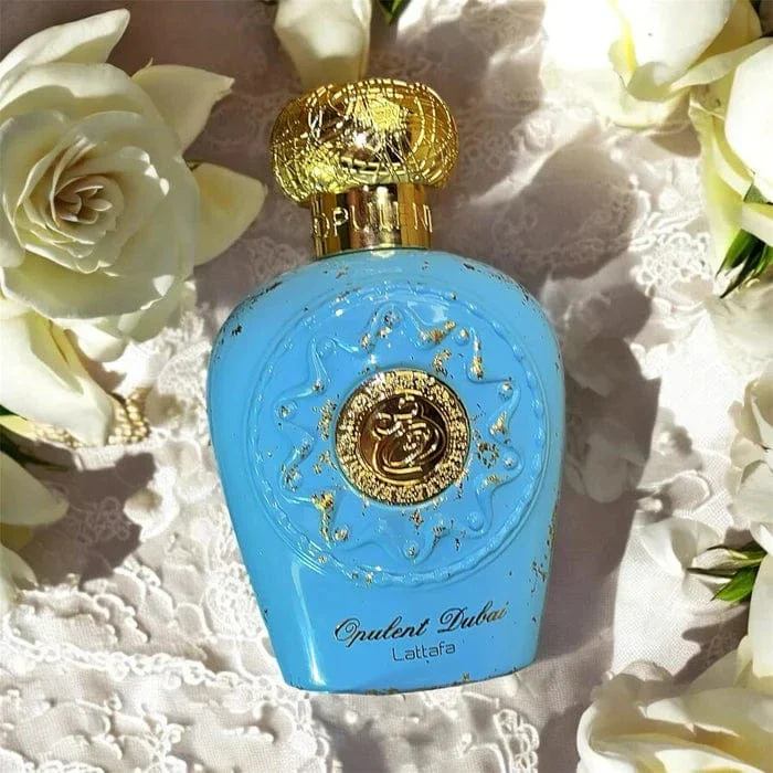 Frasco de perfume azul com detalhes dourados e tampa dourada com rosas brancas ao redor
