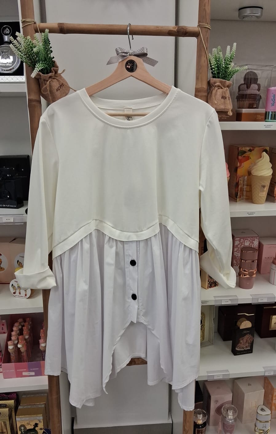 Blusa branca feminina com botões pretos e mangas compridas pendurada em cabide