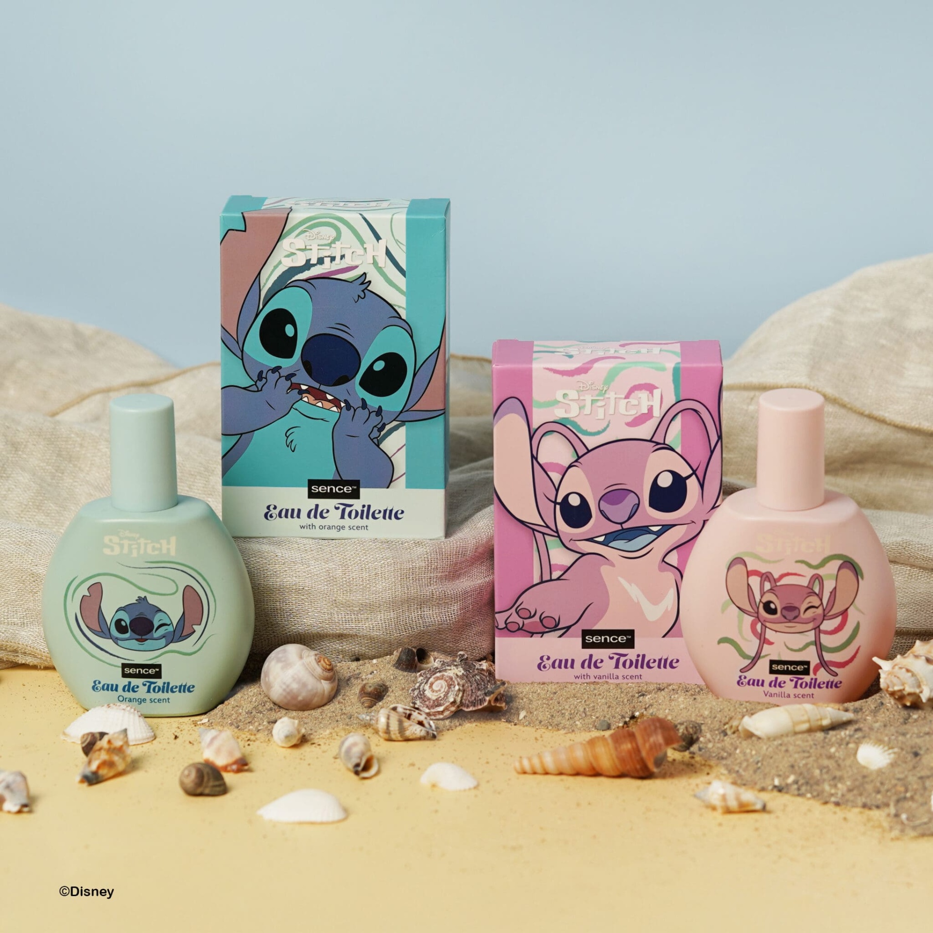 Dois frascos de perfume Disney Stitch azul claro e rosa com caixas, sobre areia e conchas.