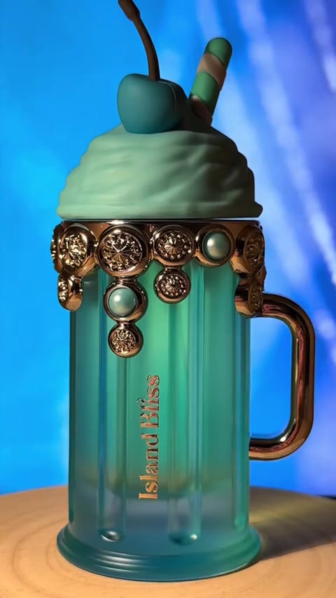 Caneca decorativa azul esverdeada com ornamentos dourados e tapa decorativa verde com cereja e pau de canela