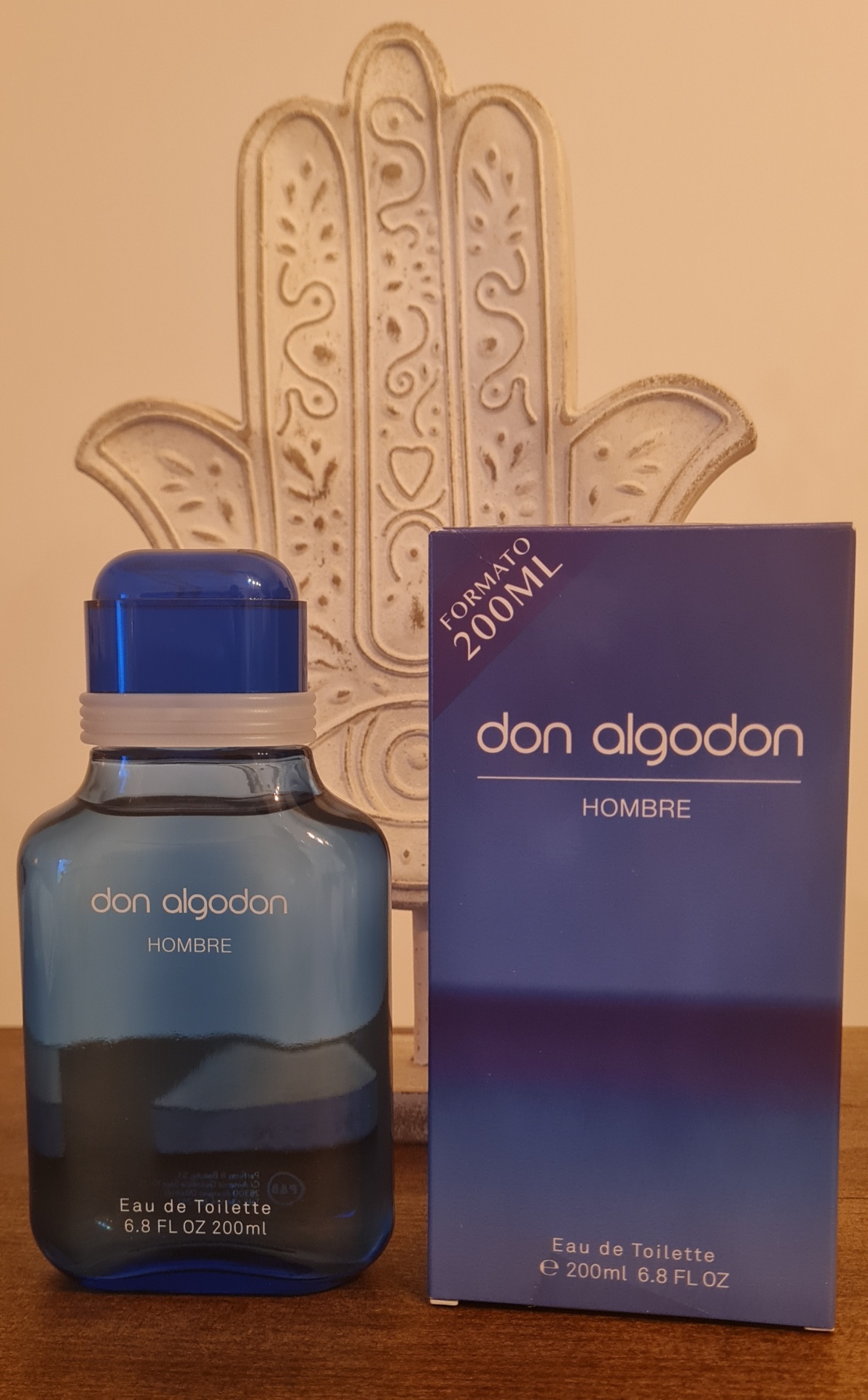 Frasco azul de Eau de Toilette Don Algodon Hombre com caixa azul e escultura decorativa ao fundo