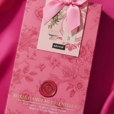 Embalagem rosa floral do conjunto ROYAL HANDBAG ESSENTIALS com selo vermelho e laço rosa.