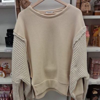 Sweatshirt bege com mangas largas em malha pendurada num cabide