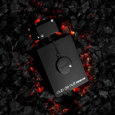 Frasco preto de perfume masculino 'club de nuit intense men' sobre carvão incandescente