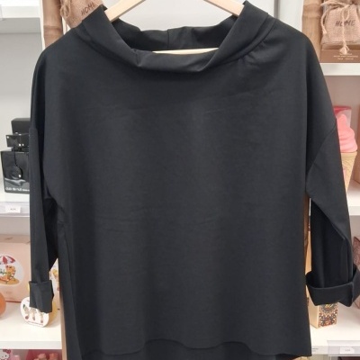 Camisola preta de mangas compridas com gola alta pendurada num cabide de madeira