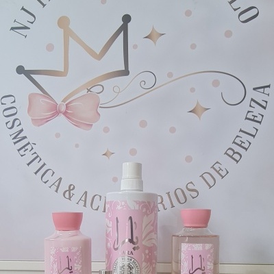 Produtos cosméticos Yara em rosa e branco sobre superfície rústica com fundo de logo em parede branca.