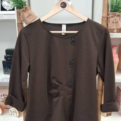 Camisola castanha de manga comprida com botões pretos numa estrutura de bambu