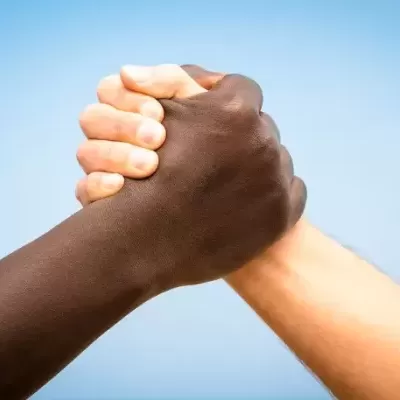 Duas mãos entrelaçadas de pele escura e clara com fundo azul
