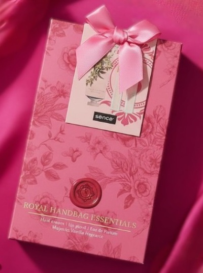 Embalagem rosa floral do conjunto ROYAL HANDBAG ESSENTIALS com selo vermelho e laço rosa.
