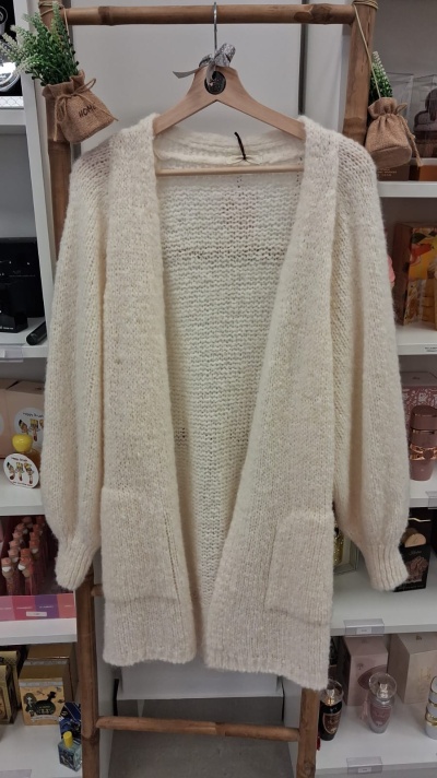 Casaco cardigan branco de malha grossa pendurado em cabide de madeira