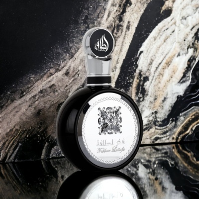 Frasco de perfume preto com rótulo prateado e tampa translúcida, em fundo marmoreado.