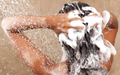 Pessoa a lavar o cabelo com espuma branca em chuveiro