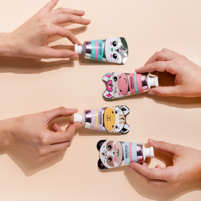 Quatro tubos pequenos de creme para as mãos com ilustrações de animais, em fundo bege