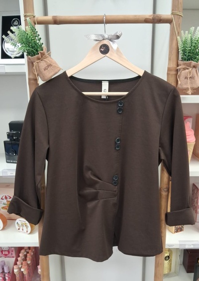 Camisola castanha de manga comprida com botões pretos numa estrutura de bambu