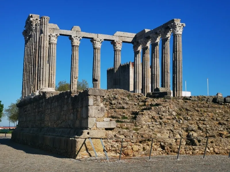 Ruínas de templo romano com colunas de pedra cinzenta e base de pedra irregular