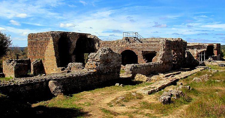 Ruínas antigas de pedra e tijolo com arcadas e relva