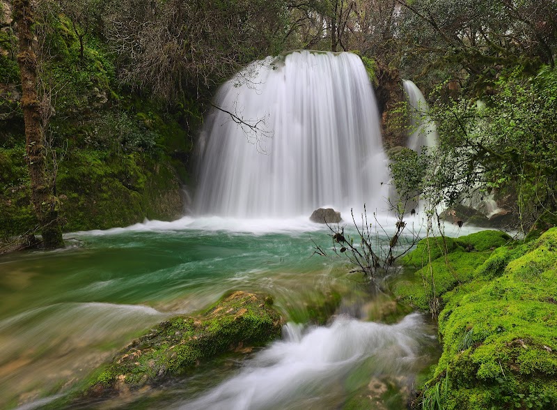 Cascata de Rio de Mouros | Conimbriga | Igreja de Santa Cruz de Coimbra Cachoeira com água esbranquiçada a cair sobre pedras verdes com musgo e vegetação ao redor