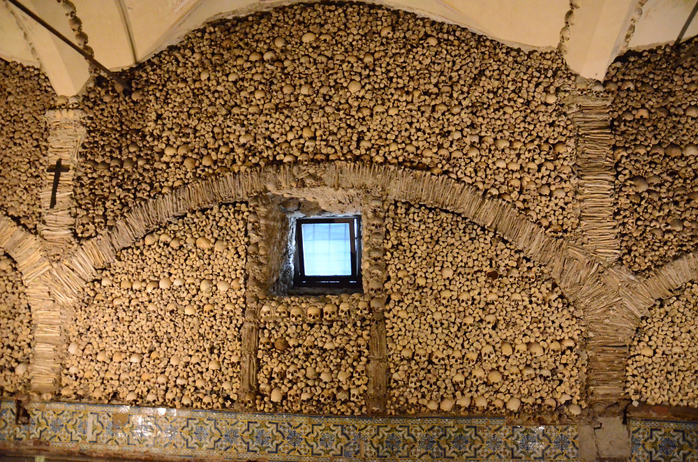 Parede com ossos humanos organizados e janela ao centro