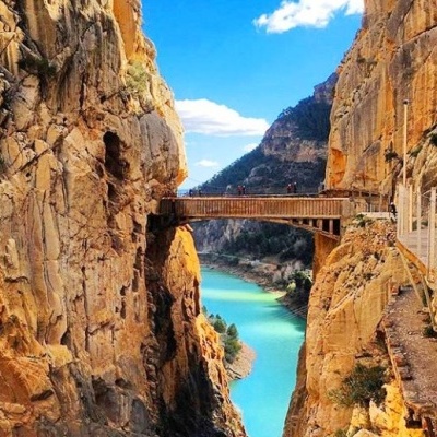 Parque natural com caminho suspenso e rio azul entre rochas amarelas