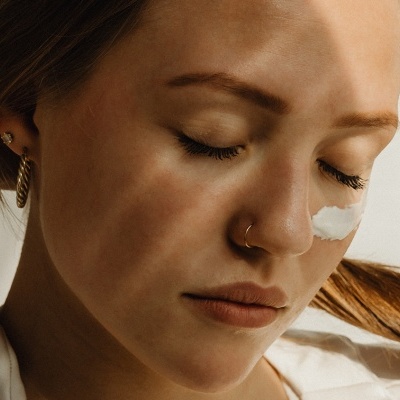 Mulher com creme branco aplicado no nariz e cabelo castanho claro