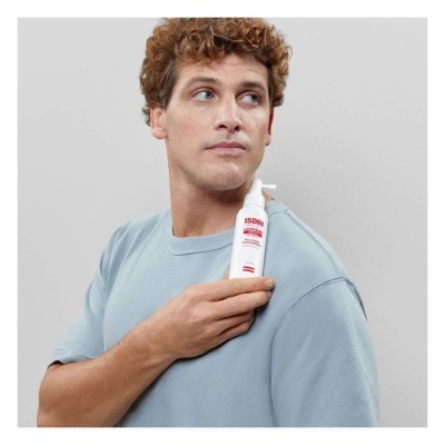 Homem com t-shirt azul claro segurando frasco branco com texto ISDIN