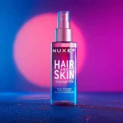 Frasco spray NUXE HAIR AND SKIN Sensual Era cor-de-rosa com fundo azul e rosa