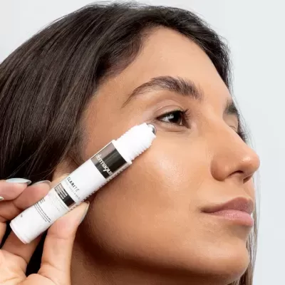 Produto cosmético branco aplicado no rosto de mulher jovem com cabelo castanho escuro