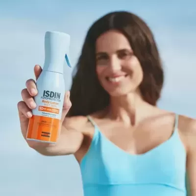 Mulher a segurar frasco ISDIN Fotoprotector Body Lotion SPF 50+
