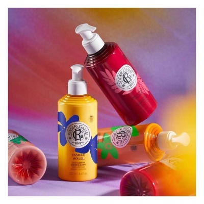 Frascos coloridos de loção corporal Roger & Gallet com flores, sobre fundo colorido