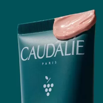 Tubo azul escuro de creme Caudalie Paris com creme rosa claro no topo