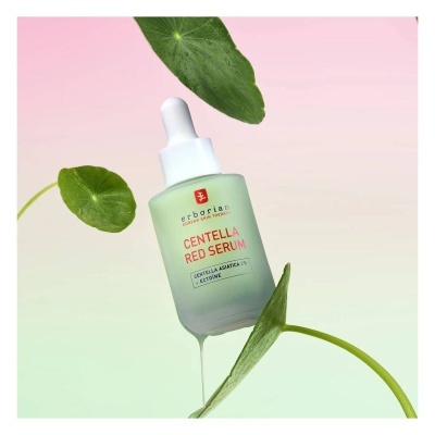 Frasco de sérum Centella Red Serum em frasco esverdeado fosco com conta-gotas branco e folhas verdes ao fundo