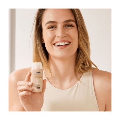 Mulher sorridente com uma camisola bege claro segura frasco de creme ISDIN FotoUltra 100 Gel Color