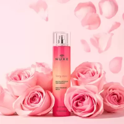 Frasco de perfume NUXE Very Rose com rosas cor de rosa ao redor