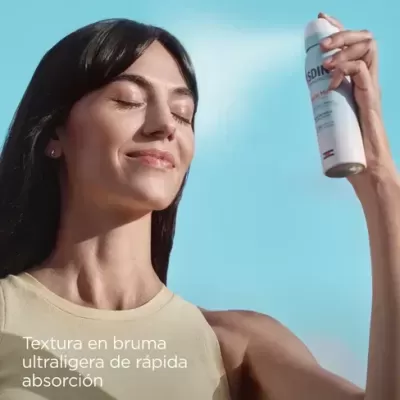 Mulher segurando spray branco ISDIN ao ar livre com céu azul