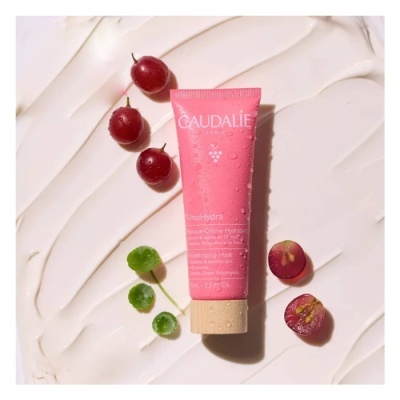 Frasco rosa de creme Caudalie com bagas vermelhas e folhas verdes sobre fundo branco