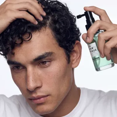 Homem aplica spray para cabelo em cabelo encaracolado preto