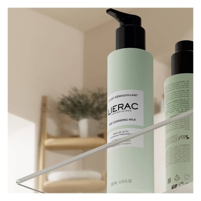 Frasco de leite de limpeza LIERAC verde claro com tampa preta em superfície espelhada com prateleira e planta ao fundo