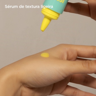 Frasco de sérum azul e amarelo gotejando sérum amarelo na mão