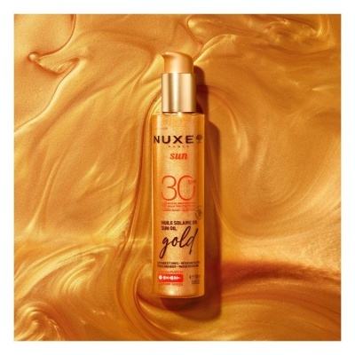 Frasco dourado de óleo solar NUXE Sun SPF 30 com doseador em fundo dourado