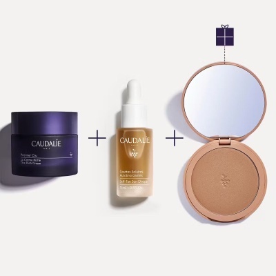 Três produtos Caudalie em fundo branco, incluindo creme em frasco roxo, sérum dourado com conta-gotas e pó bronzeador em estojo com espelho.