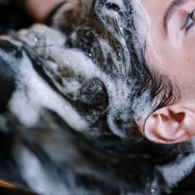 Pessoa a lavar o cabelo com espuma branca