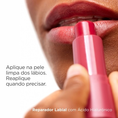 Batom rosa escuro sendo aplicado nos lábios com texto em português sobre uso do reparador labial