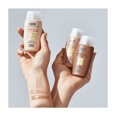 Frascos de protetor solar ISDIN Fusion Water Color & Care SPF 50+ em tons castanhos mostrados em mãos com amostras no braço