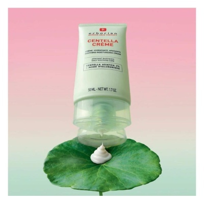 Tubo de creme hidratante branco com tampa transparente sobre folha verde com creme espiralado e fundo rosa-esverdeado