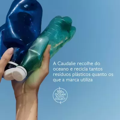 Mão segurando duas garrafas plásticas amassadas contra céu azul com texto em português