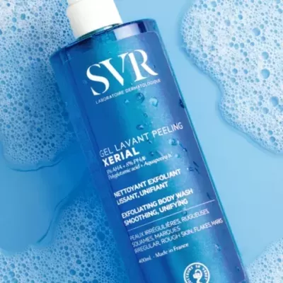 Frasco azul de gel de limpeza corporal SVR Xerial com tampa branca sobre fundo azul com espuma