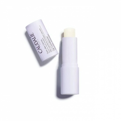 Bálsamo labial Caudalie em tubo lilás aberto sobre fundo branco