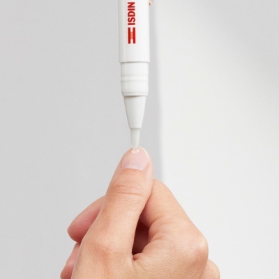 Caneta aplicadora branca ISDIN a aplicar produto na unha