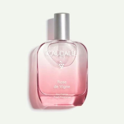 Frasco de perfume rosa Caudalie com tampa prateada